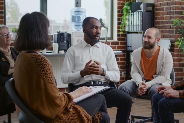 African american man sharing addiction story with group of people at aa therapy meeting