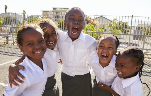 Young African schoolgirls in playground smiling to camera